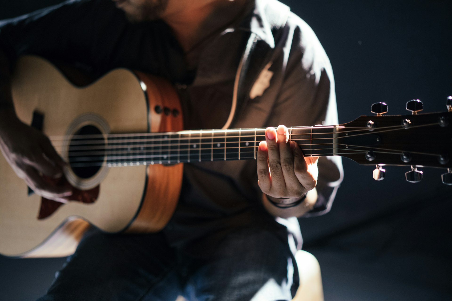 Musician performing with a guitar under stage light