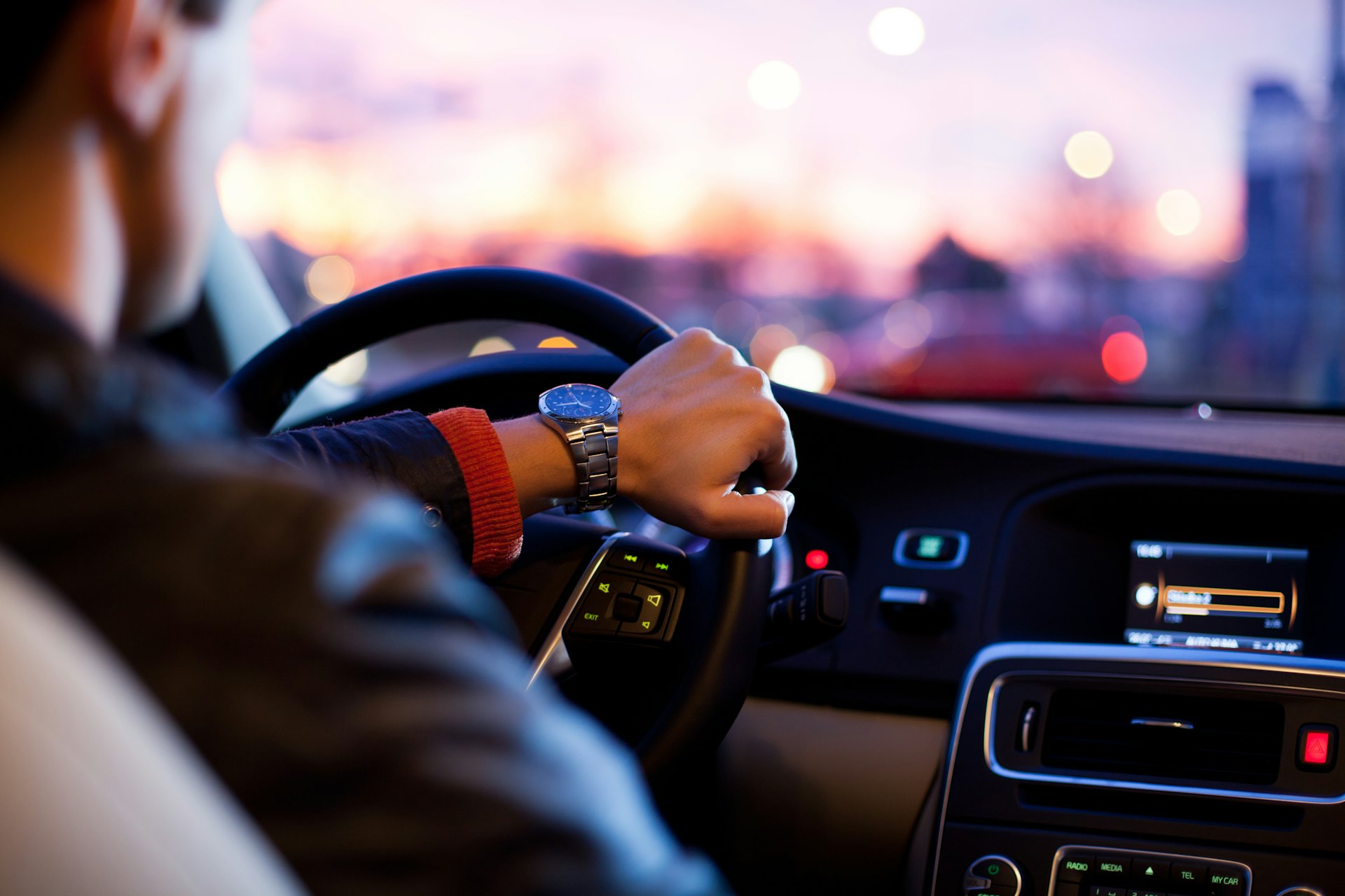 Driver's hands on the wheel while approaching an evening arrival route